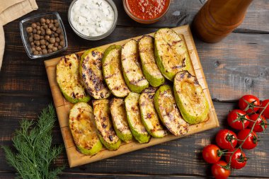 Koyu ahşap masada soslu ızgara kabak.