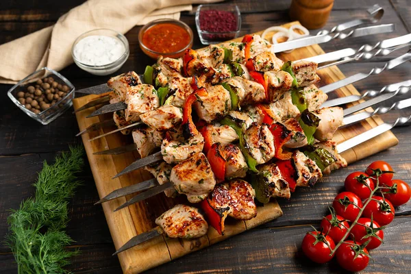 Turkey or chicken shish kebab on metal skewers with pepper tomatoes and onion on rustic wooden table background