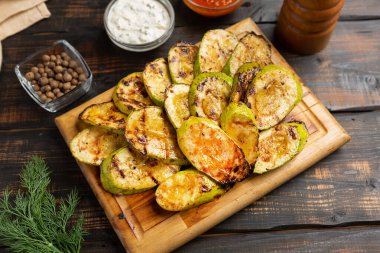 Koyu ahşap masada soslu ızgara kabak.