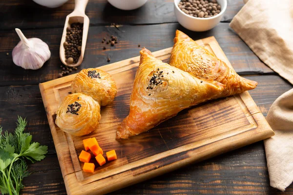 Uzbek national dish samsa or samosa with meat or vegetables and pumpkin on cutting board with spice