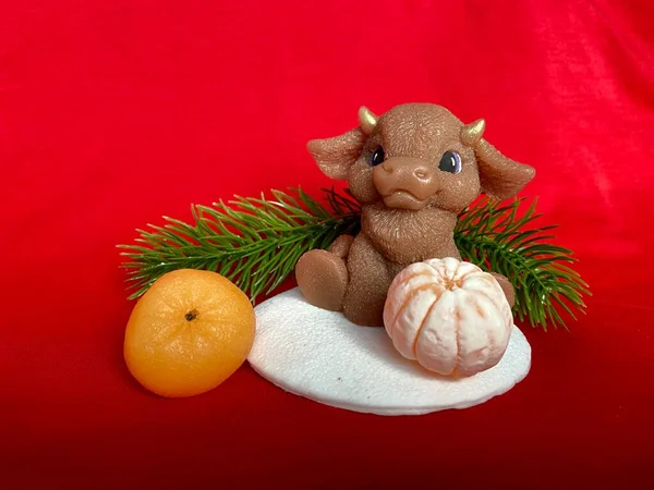 Bull as a symbol of the New year 2021. Soap ox with mandarin and Christmas tree on the red background. Christmas concept.
