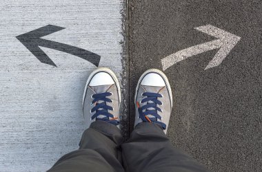 Sneakers standing on a road with arrows. clipart