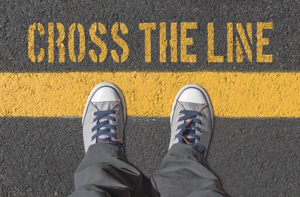 Sneakers standing on the yellow line. — Stock Photo, Image