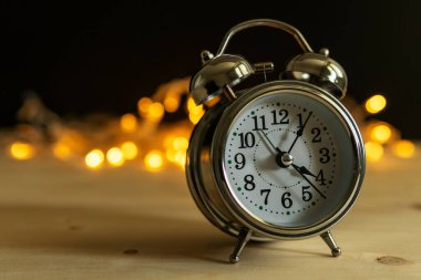 Arka planda Noel ışıkları olan klasik çalar saat.