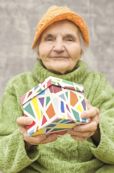 Bir hediye kutusu tutan yaşlı kadın. — Stok fotoğraf