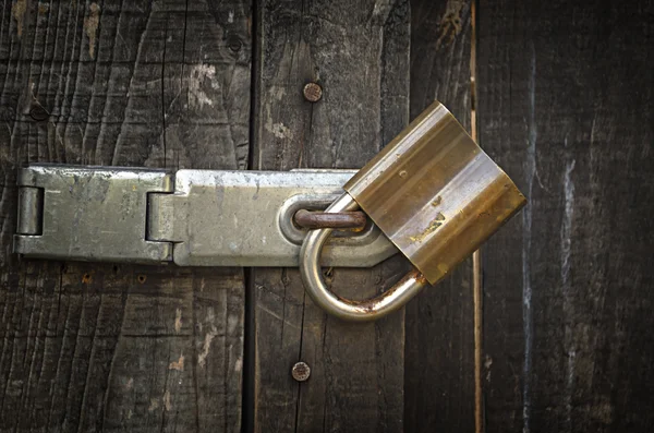 Candado y viejo hasp de metal en una vieja puerta de madera — Foto de Stock