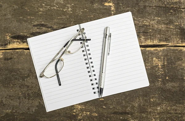 Lege Kladblok met pen en bril op houten tafel. — Stockfoto