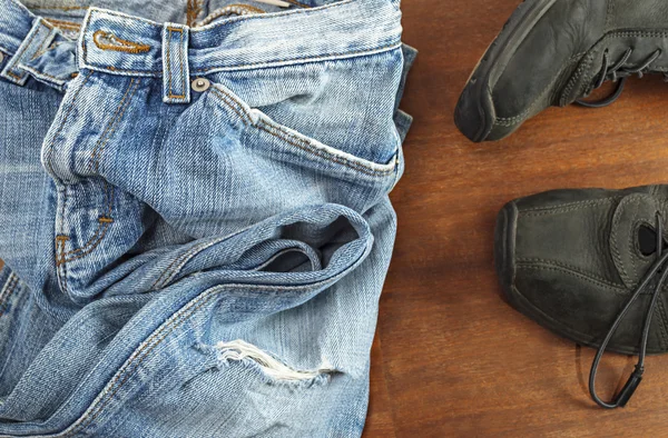 Blue jeans with black shoes on wooden background — Stock Photo, Image