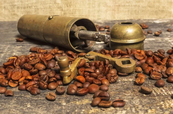 Granos de café con molinillo de café en mesa de madera —  Fotos de Stock