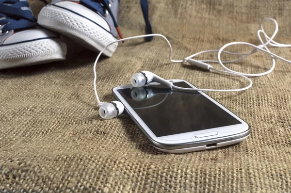 Smart phone on a table cloth with sneakers. — Stock Photo, Image