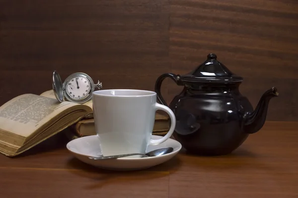Tazas de té con tetera, libros y reloj de bolsillo viejo en mesa de madera —  Fotos de Stock