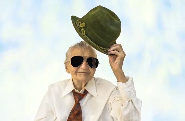 Äldre kvinna leende med en hatt i handen. — Stockfoto