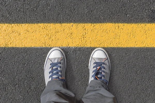 Sarı sokak satırlarının yanında ayakta.