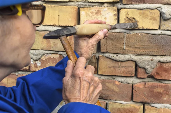 Elderly woman holding a hammer and chisel. — Stock Photo, Image