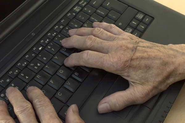 Closeup on elderly hands on keyboard of laptop. — Stock Photo, Image