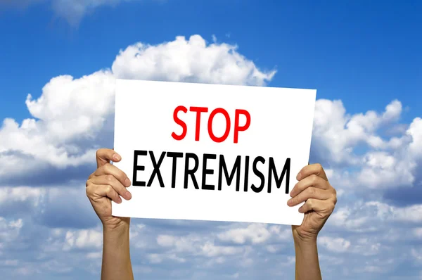 STOP EXTREMISM tarjeta en la mano contra el cielo azul con nubes . —  Fotos de Stock