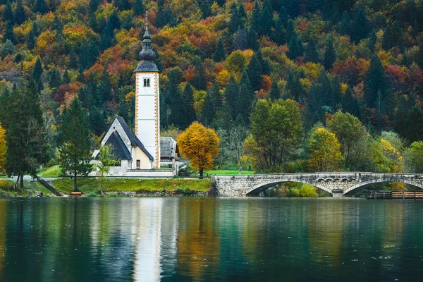 Hermosa vista de colorida escena otoñal de la famosa Iglesia de San Juan Bautista, Lago Bohinj, Ribicev Laz, pueblo turístico en Eslovenia —  Fotos de Stock