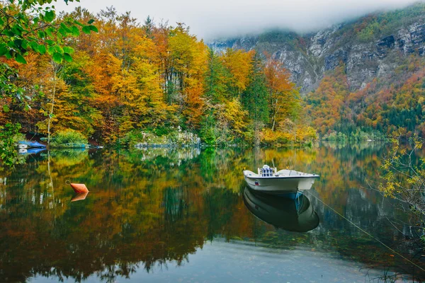 Autumnal scenic view of boat on the Bohinj lake surrounded by colorful forest — Stock Photo, Image