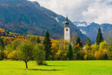 Bohinj Gölü'nde ünlü St John The Baptist Kilisesi renkli sonbahar sahnesinin muhteşem görünümü. Arka planda Vogel dağı. Ribicev Laz, Slovenya'nın turistik köyü