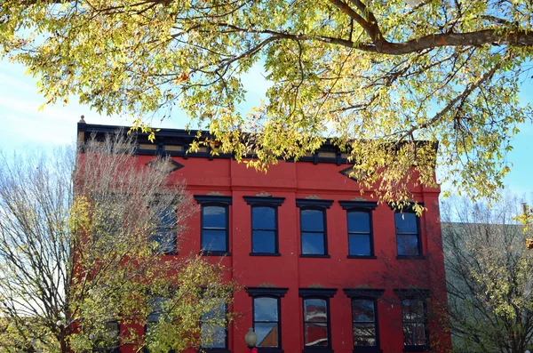 Autumn branches framing an old red building — Stock Photo, Image