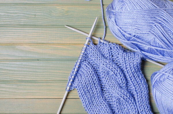 Balls of blue yarn and knitting needles. Wooden background. Copy space. The concept of women 's needlework.