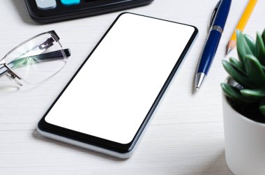 Beyaz bir masada boş ekranı olan bir akıllı telefon. Uzayı kopyala Çevrimiçi yatırım, iş veya hisse senedi ticareti kavramı.