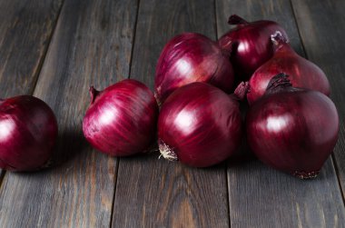Kahverengi ahşap arka planda bir sürü kırmızı soğan.