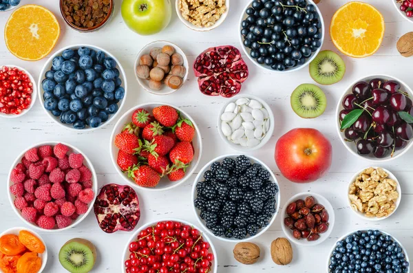 Taze böğürtlen, meyve, beyaz ahşap arka planda fındık. Sağlıklı beslenme kavramı. Yiyecek vitamin ve eser elementler içerir.