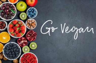 Yüksek oranda antioksidan içeren yiyecekler: böğürtlen, fındık, meyve. Siyah beton arka plan. El yazması yazı: Git Vegan