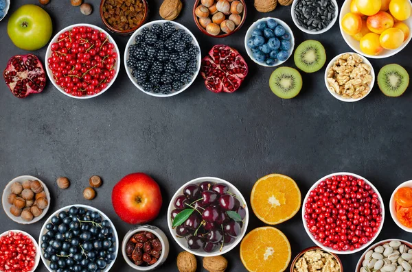Alimentos com alto teor de antioxidantes: bagas, nozes, frutas. Fundo de concreto preto. Espaço de cópia Fotografia De Stock