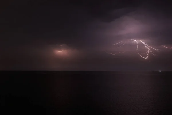 Thunderstorm with lightning over the sea at night. Lightning flashes and storm clouds