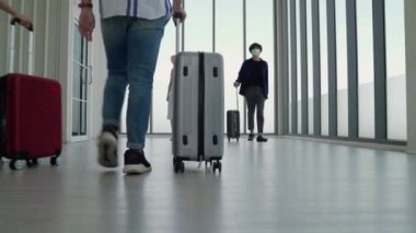 Coronavirus salgınının ortasında, maskeli turistler havaalanı salonlarında birbirlerini selamlıyorlar..