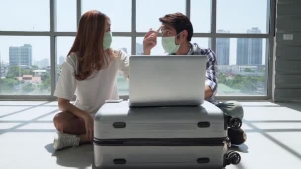 在机场休息室 一对夫妇戴着口罩 以防止Covid 用放在手提箱上的笔记本计划旅行 — 图库视频影像