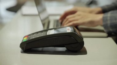 Otel resepsiyonundaki tezgahın üzerinde, fatura ödemek için kredi kartı veya kredi kartını çalarken kredi kartı terminali ile el yapımı ödemeyi kapat.