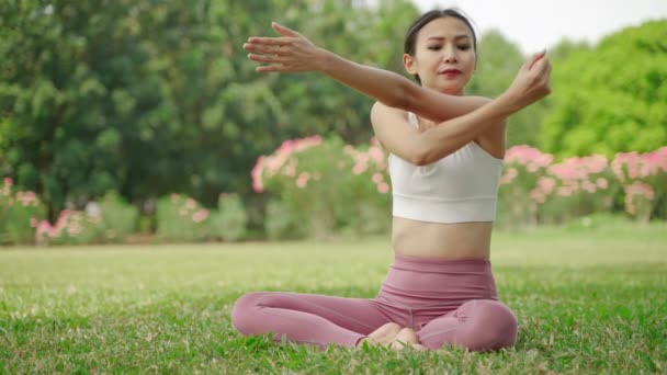 年轻的亚洲女人正坐在花园里练瑜伽 她很放松 也很喜欢运动 — 图库视频影像