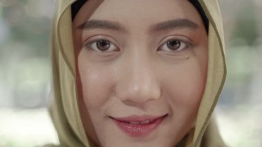 Yakın plan video, gülümseyen Müslüman bir kadının yüzü.