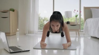 Genç Asyalı kadınlar sosyal uzaklık sırasında online egzersiz yaparak yatak odası tahtası egzersizi yapıyorlar.