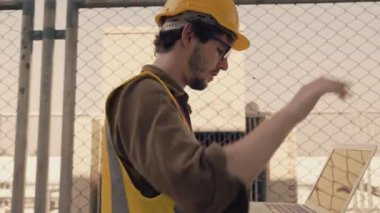 İşçi ya da mühendis, fabrikanın çatısındaki trafoları inceliyor..