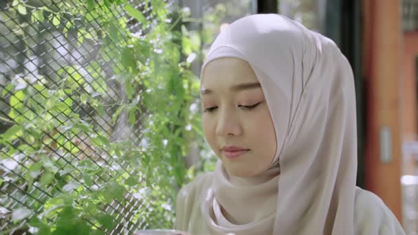 美丽的穆斯林女孩 头戴头巾 一边喝着咖啡一边沉思故事 — 图库视频影像