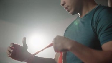 Asyalı boksör pratik yaparken eldivenlerini giymeden önce elini sarar. koyu ton