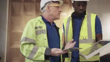 Mühendislerin 50 poundluk çerçeve görüntüleri binaya güneş panellerini nasıl kuracaklarını tartışıyor. Yenilenebilir Enerji kavramı, Dünyayı Kurtarma