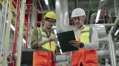 Mühendis ve Foreman 'ın 50 penilik çerçeve görüntüsü fabrika kazan dairesinin planının planlarını tartışıyor.