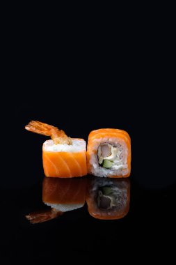 Siyah masada çubuklarla servis edilen lezzetli suşi dürümleri.