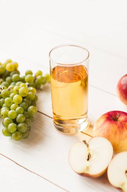 Beyaz arka planda yeşil yapraklı taze üzüm meyveleri. Bir demet yeşil üzüm ve meyve suyu, sürahi.