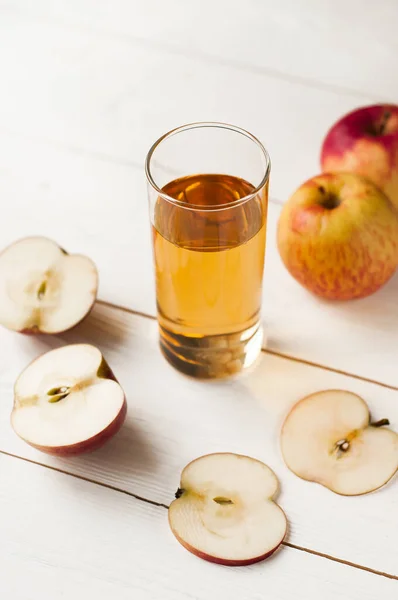 apple juice in a glass and apples on wooden background. Healthy apple juice drink and red apples fruits in autumn
