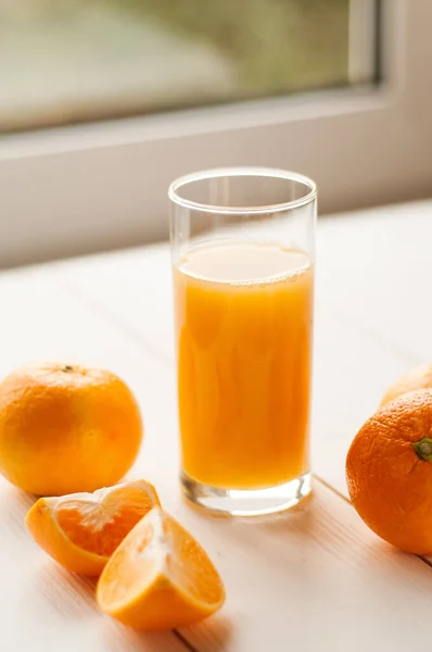Orange juice and ripe orange on a white wooden background. refreshing drinks, grapefruit juice with rosemary and ice on a white wooden table.
