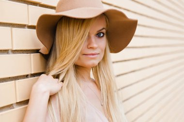 Sarı saçlı, zarif elbiseli ve şapkalı neşeli bir genç kız.