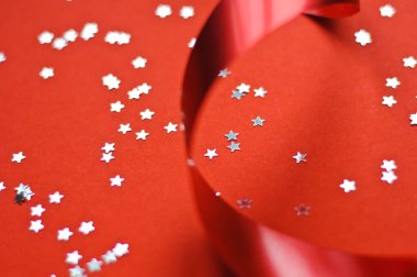 Kırmızı arkaplanda kırmızı kurdele ve parıldayan yıldızlar.