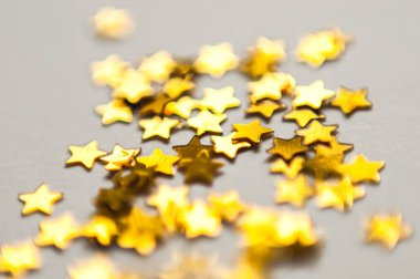 Beyaz kâğıt üzerinde yıldız şeklinde renkli konfeti. Kartlar için evrensel şablon, selamlar. Holografik leylak pulları. Makro fotoğraf, doğal ışık, bokeh.