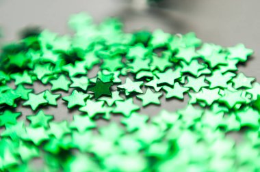 Beyaz kâğıt üzerinde yıldız şeklinde renkli konfeti. Kartlar için evrensel şablon, selamlar. Holografik leylak pulları. Makro fotoğraf, doğal ışık, bokeh.